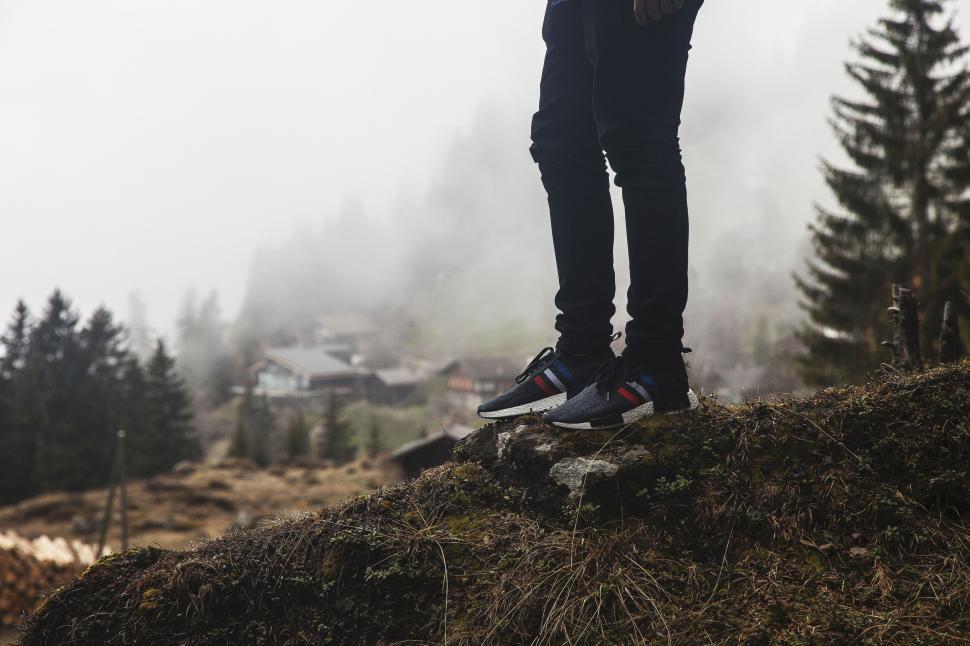 Free Image of Person standing on a hill in foggy mountains wearing sneakers. 