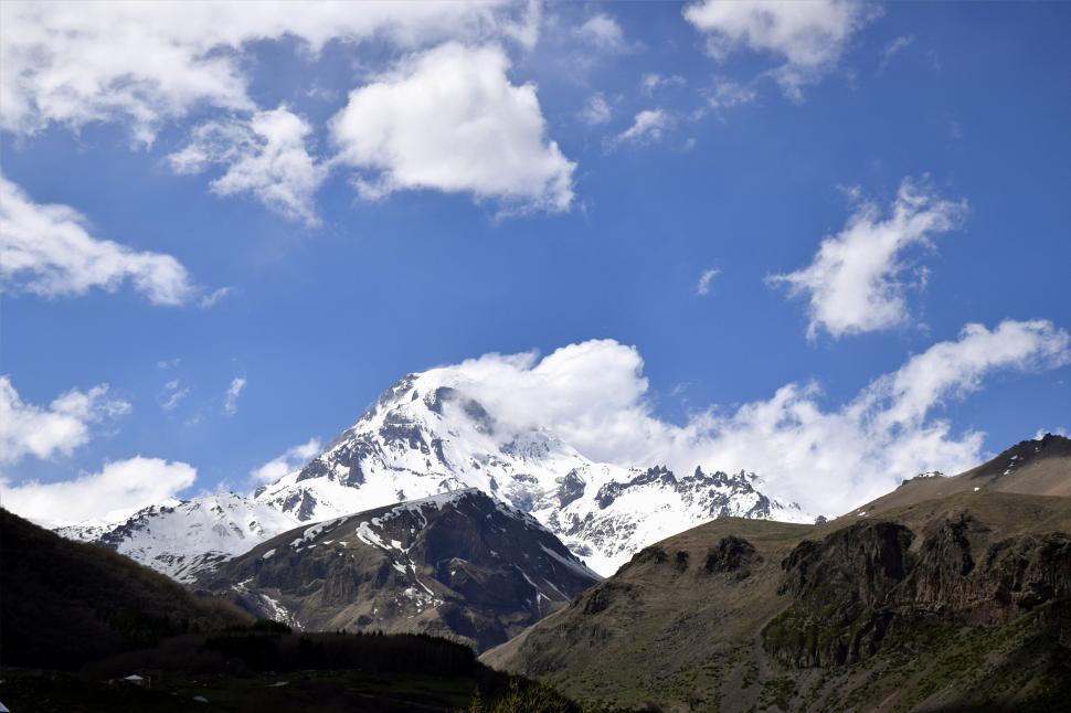 Free Image of Snow-capped mountain peak under a blue sky with scattered clouds. 