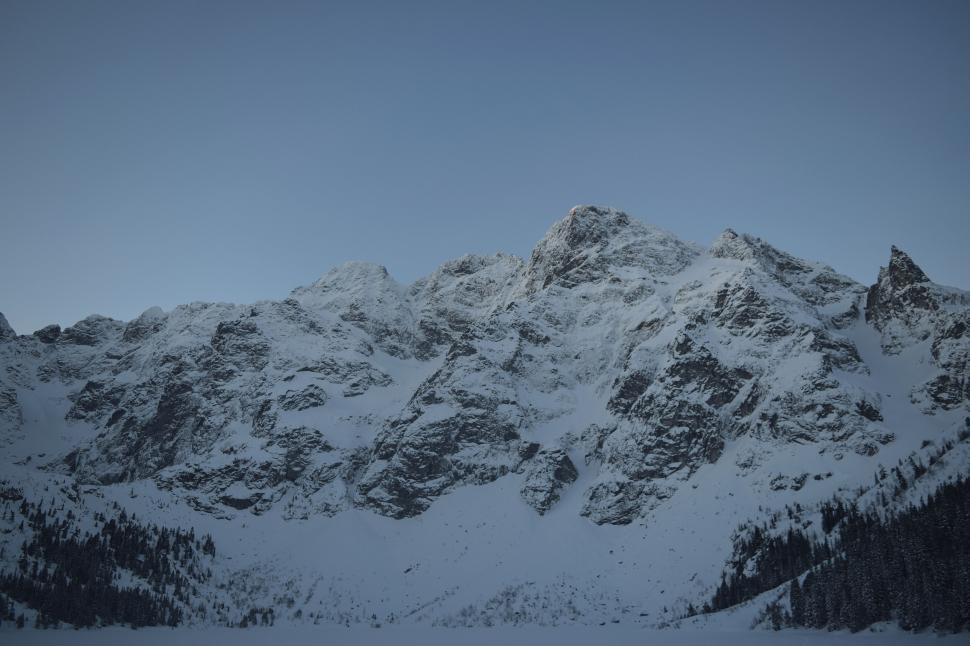 Free Image of Snow-covered mountains under a clear blue sky on a winter day. 