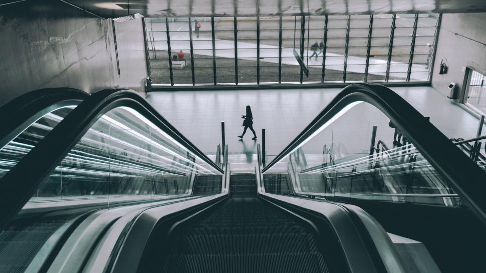 Free Image of Single person walking at the bottom of an indoor escalator. 