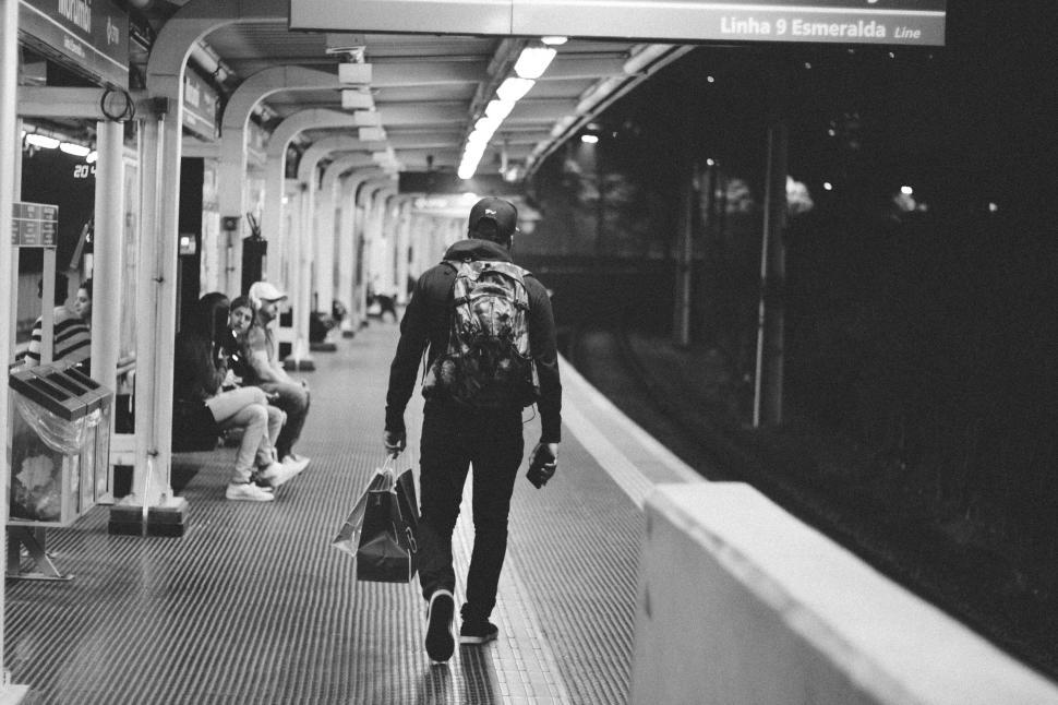 Free Image of Black and white photo of a lone traveler at an empty train station. 