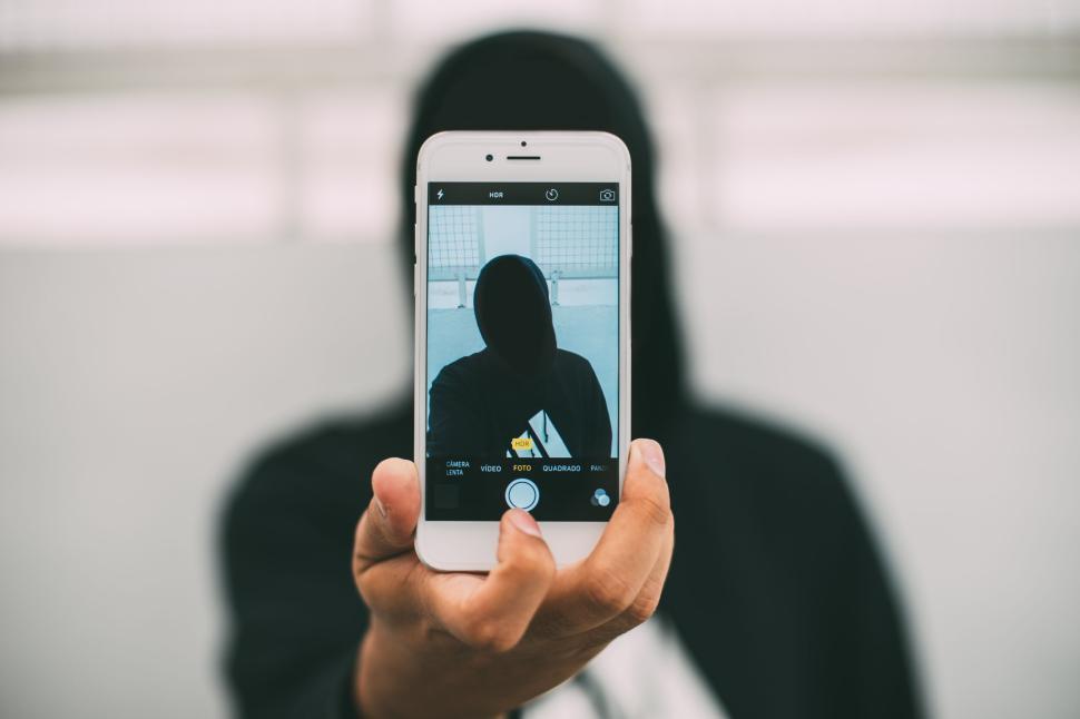 Free Image of Silhouette person holding phone camera capturing a selfie picture. 