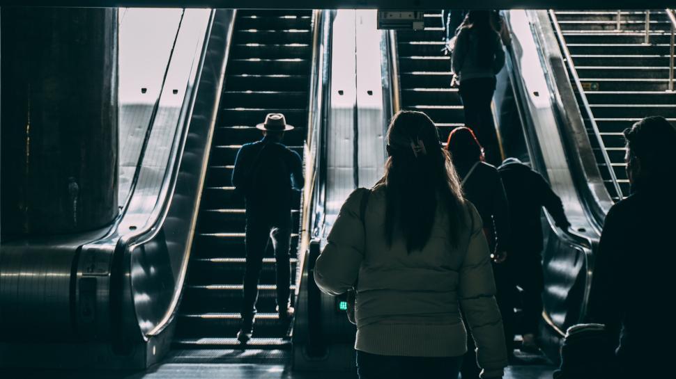 Free Image of People using escalators inside a dimly lit public transportation hub 