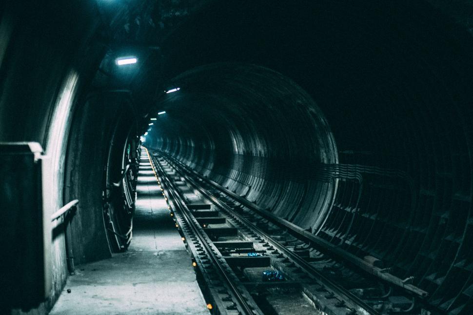 Free Image of Underground railway tunnel with leading tracks and faint lighting. 