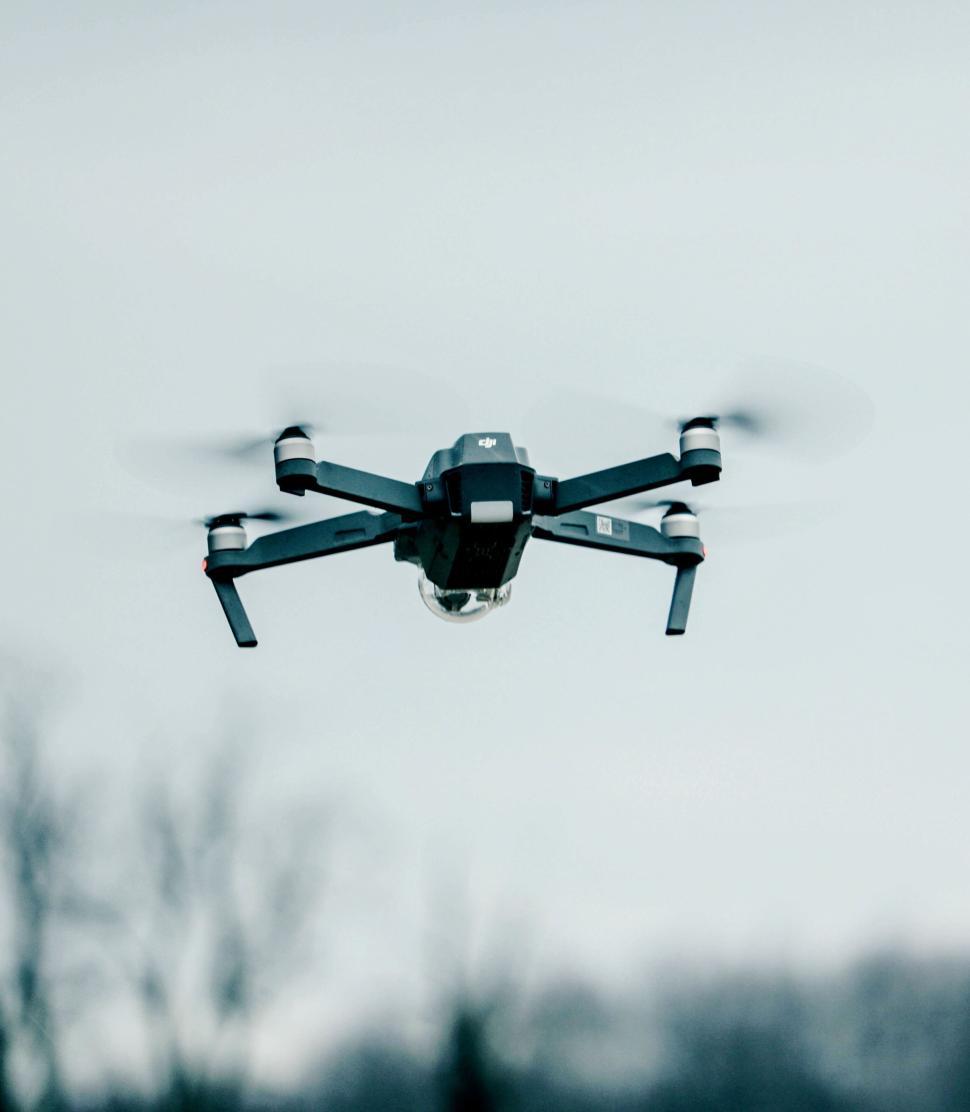 Free Image of High-tech drone hovering mid-air with blurred background details 