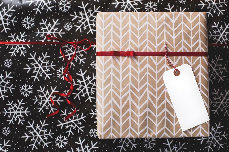 Free Image of Wrapped gift box with ribbon on snowflake-patterned paper background 