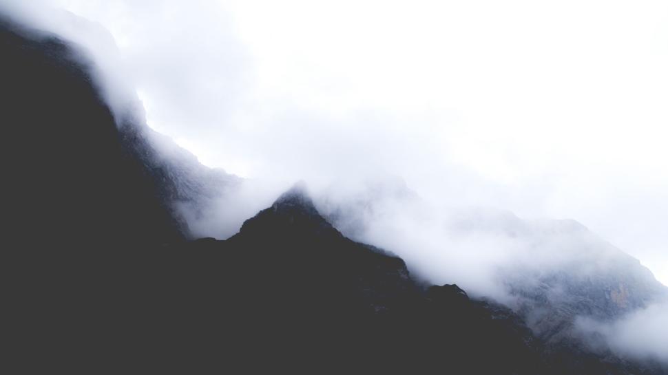 Free Image of Fog and mist enveloping dark mountain peaks creating a mystical aura. 