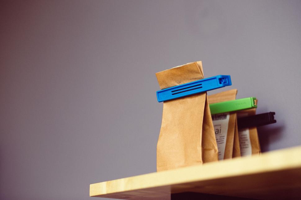 Free Image of Brown paper bags clipped with colorful clips, placed on a shelf 