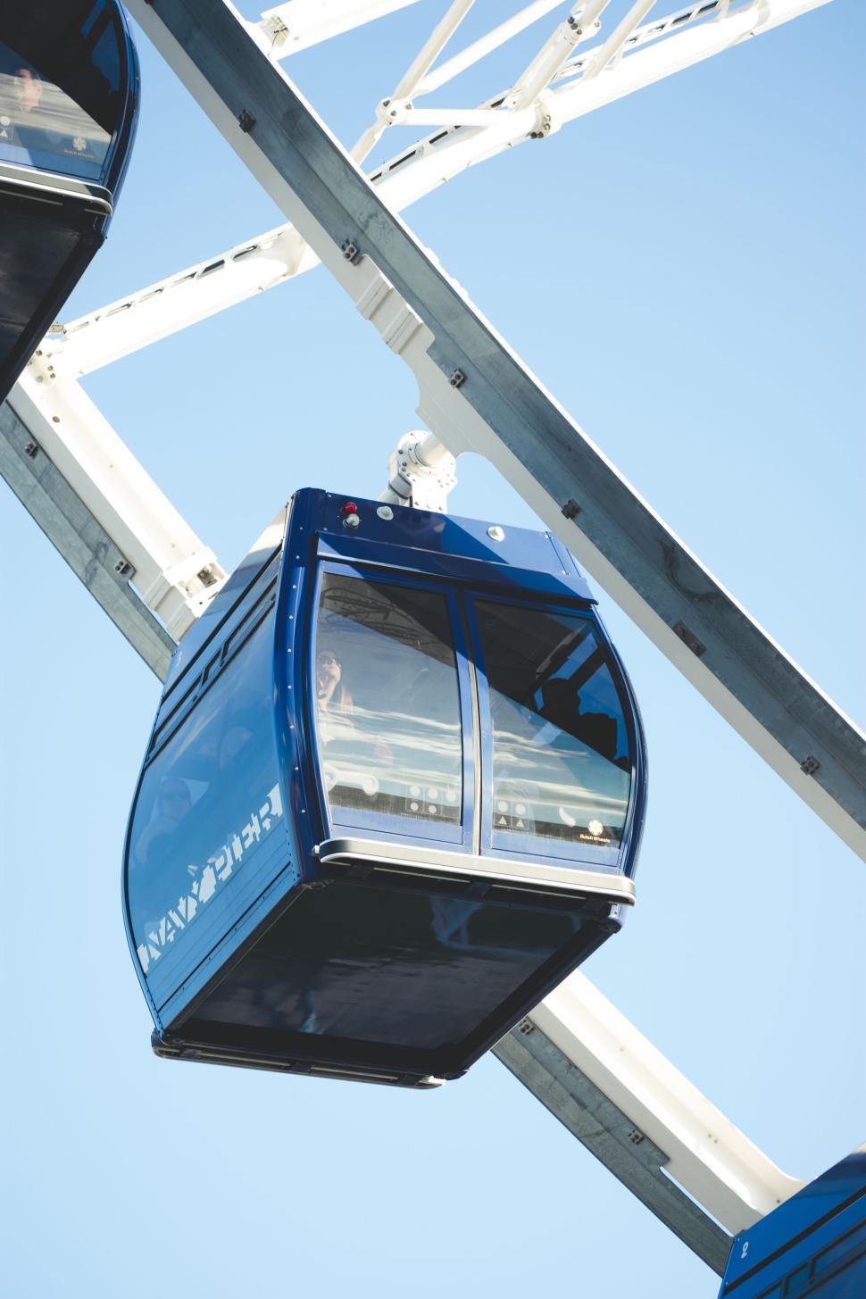 Free Image of Blue gondola on Ferris wheel against a clear sky background 