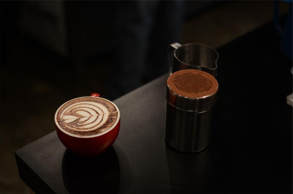 Free Image of A cup of latte art with a stainless steel container beside it 
