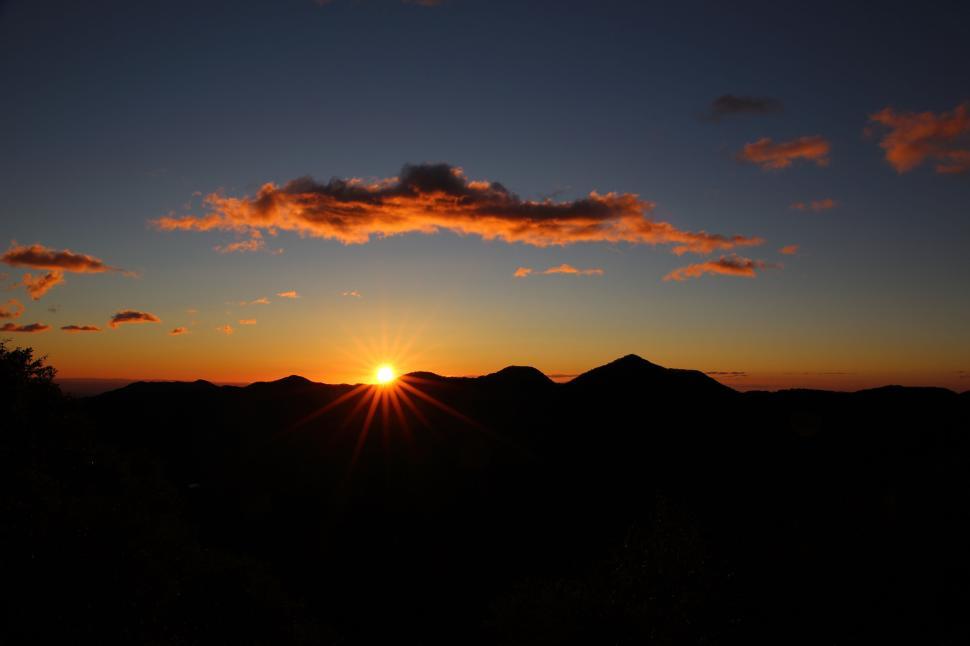 Free Image of Sunset over mountain range with orange glow and unique clouds 