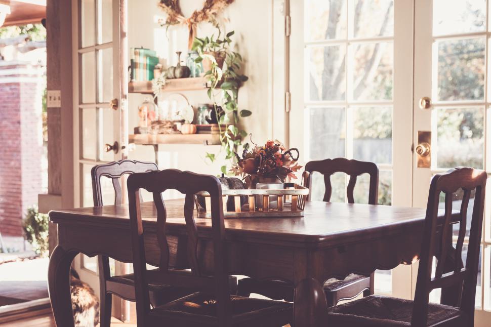 Free Image of Cozy dining room with wooden table and chairs, full of light. 