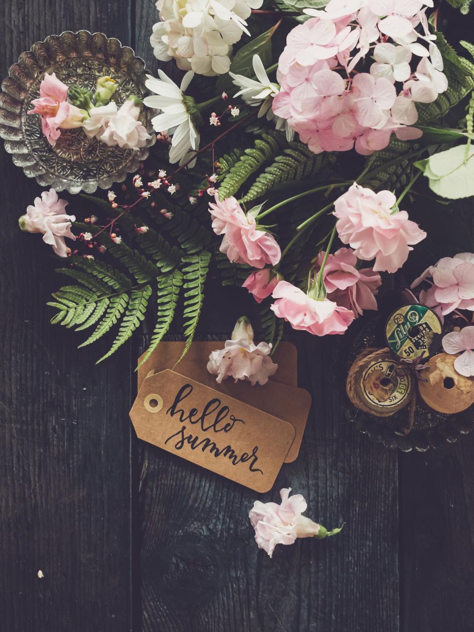 Free Image of Beautiful flowers with  Hello Summer  tag on a wooden background 