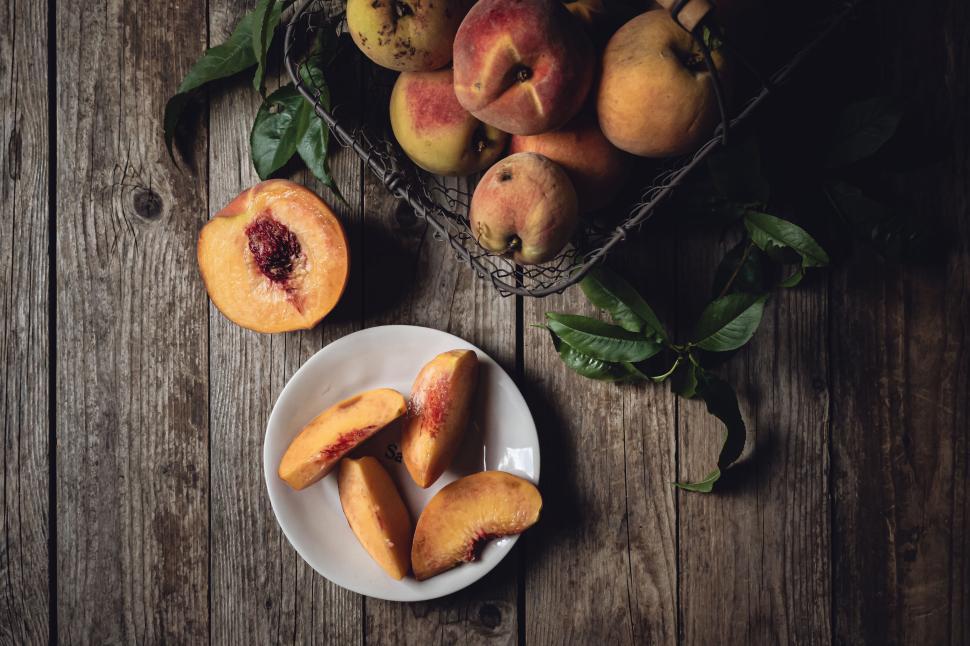 Free Image of Freshly sliced peaches on a white plate over rustic wooden background 