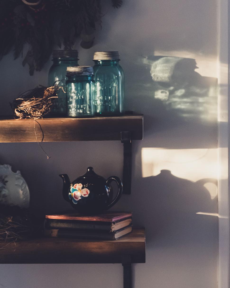Free Image of Rustic shelves with vintage jars, books, and teapot in afternoon light. 