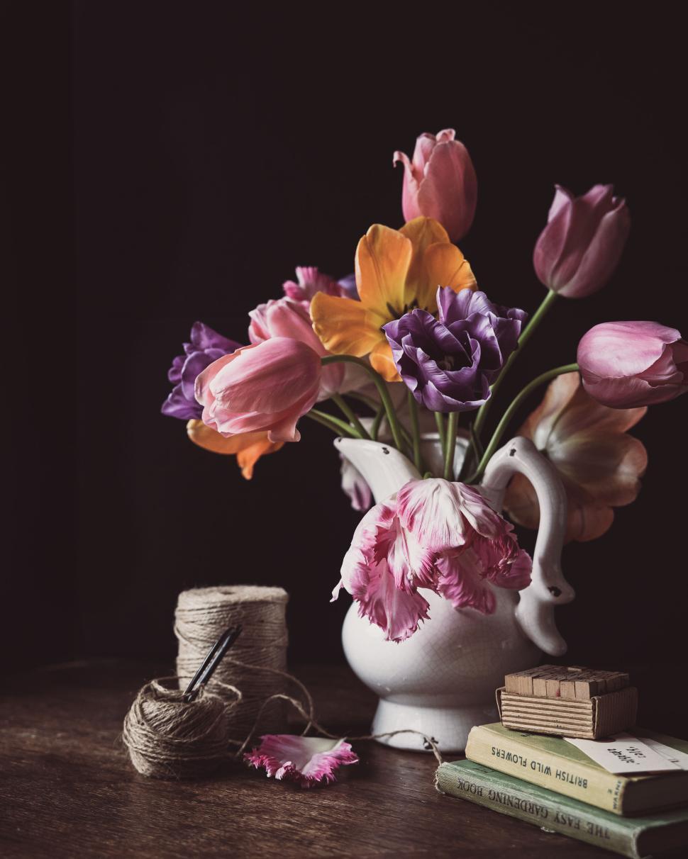 Free Image of A vase filled with tulips and other flowers on a wooden table indoors. 