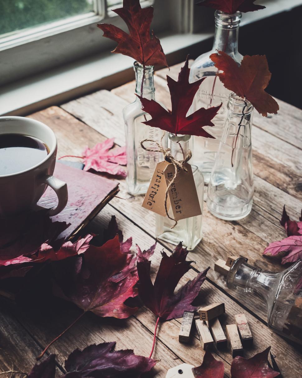 Free Image of Rustic wooden table adorned with autumn leaves and glass bottles 