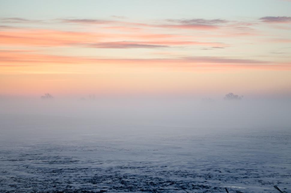 Free Image of Foggy landscape at dawn with a serene sky and subtle colors 