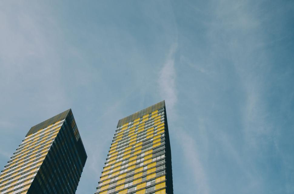 Free Image of Two modern high-rise buildings against a clear blue sky above. 