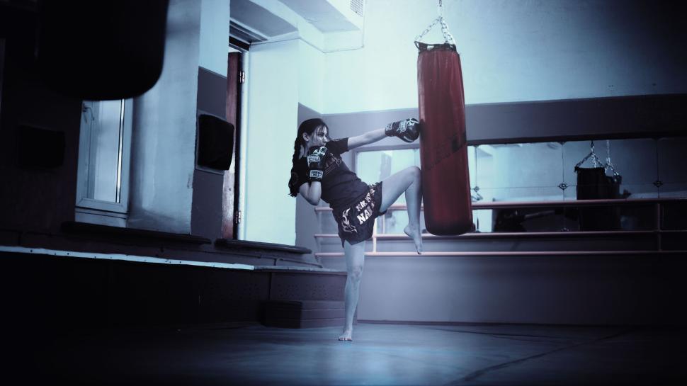 Free Image of Martial artist practicing high kick in training gym with punching bag. 