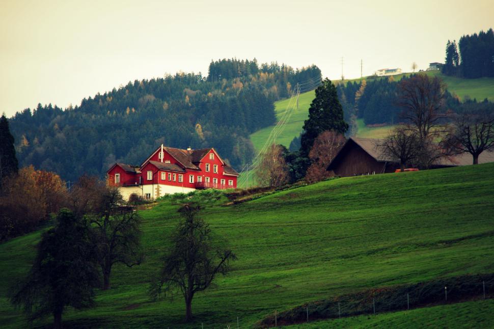Free Image of Charming countryside house with lush greenery and hilly backdrop. 