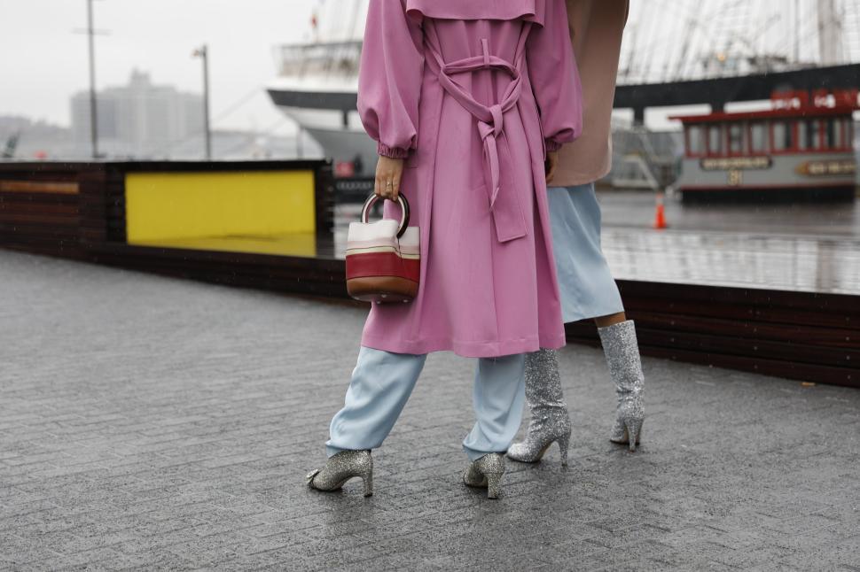 Free Image of Fashionable individuals in vibrant coats walk by a docked ship 