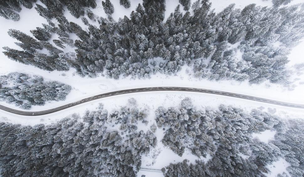 Free Image of Bird s eye view of a winding road cutting through snow-covered forest. 