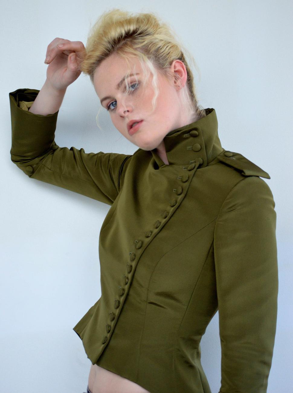 Free Image of Blonde woman stylishly posing in olive green fashionable jacket 