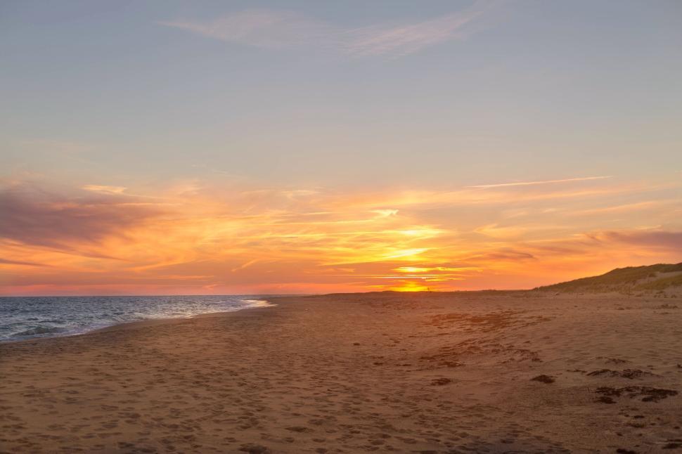 Free Image of Beautiful beach sunset with vibrant colors over sandy shoreline. 