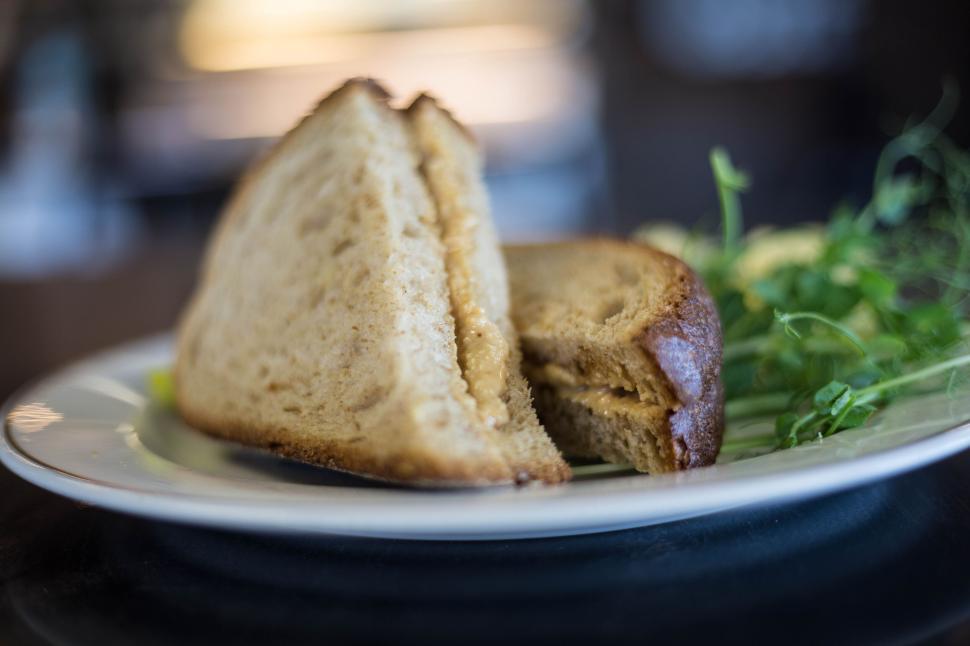 Free Image of Close-up of a sandwich on a white plate with fresh greens beside it. 