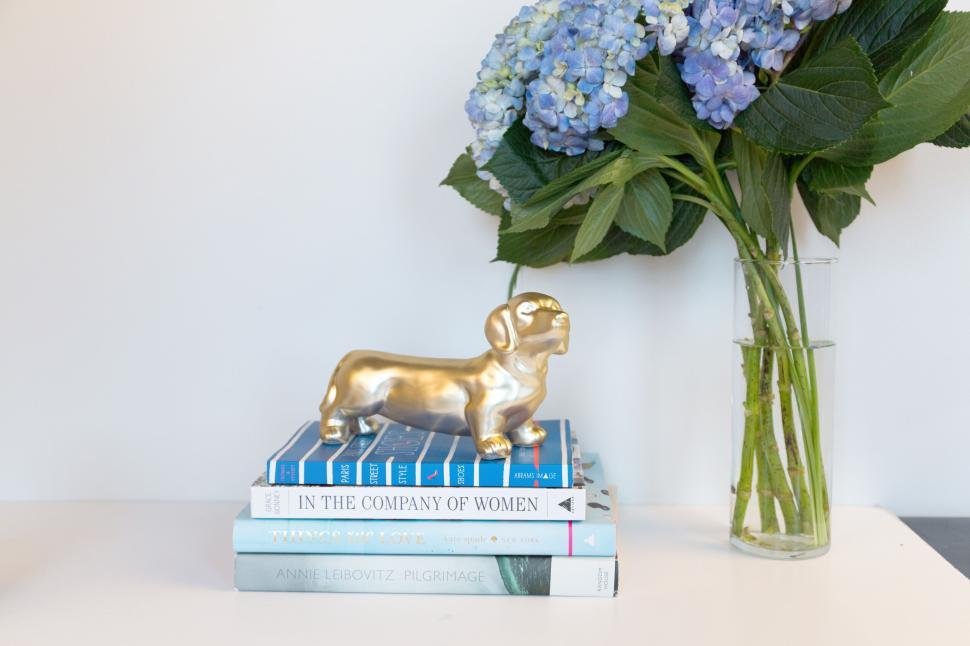 Free Image of Elegant golden dog statue on stacked books with blue flowers 