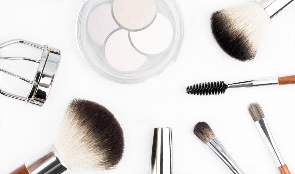 Free Image of Assorted makeup tools including brushes and eyelash curler on white. 