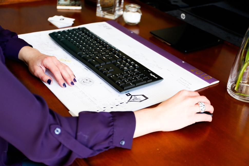 Free Image of Person working on computer at desk with keyboard and documents 