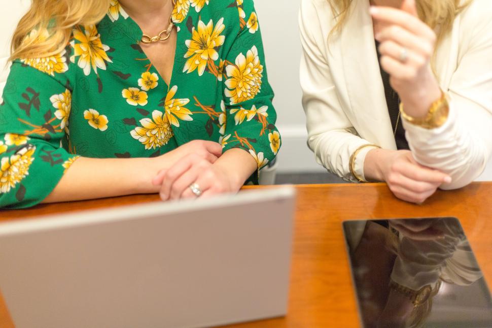Free Image of Two women seated at table working on laptop and tablet 