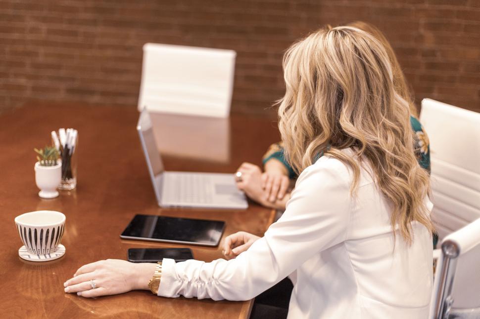 Free Image of Two women at a meeting table using a laptop and tablet computer. 