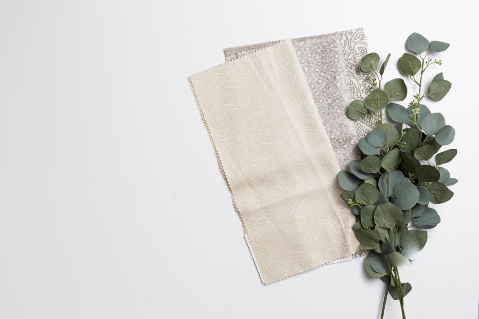 Free Image of Assorted fabric swatches and eucalyptus leaves on a white surface. 