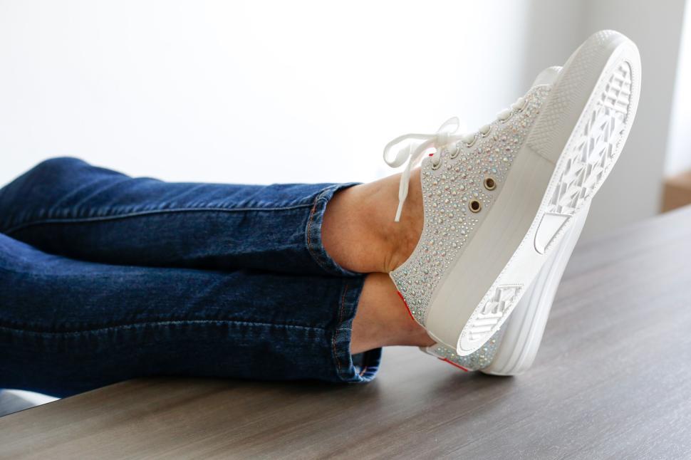 Free Image of Person relaxing with stylish white sneakers sitting feet up. 