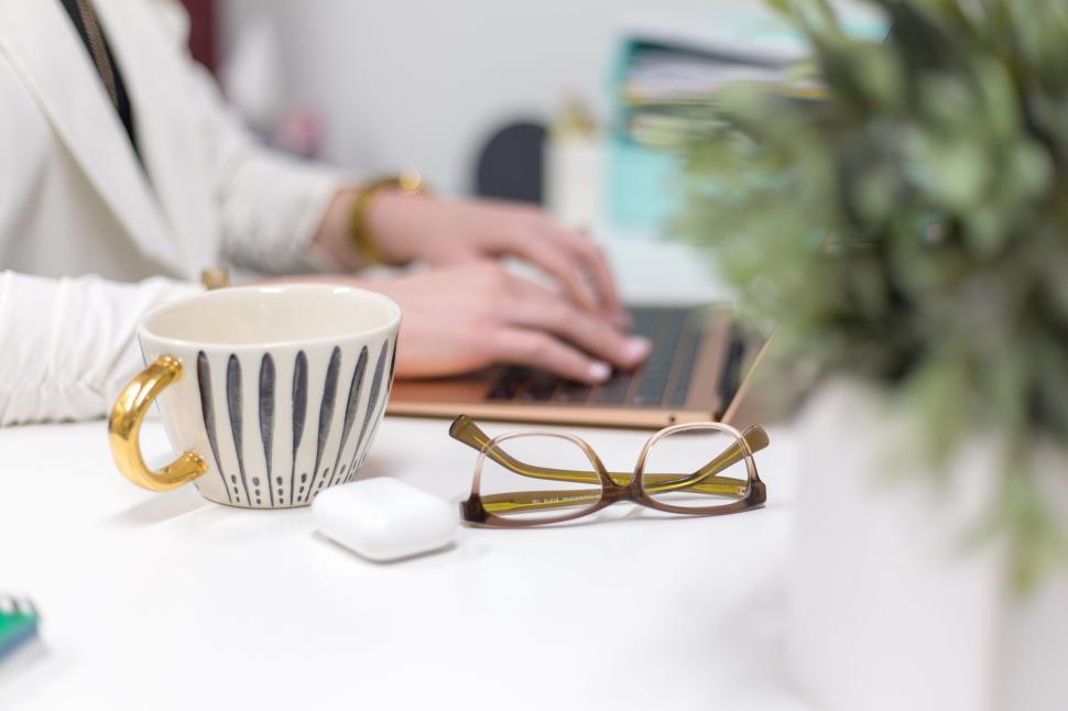 Free Image of Person typing on laptop with coffee and glasses on a neat desk 