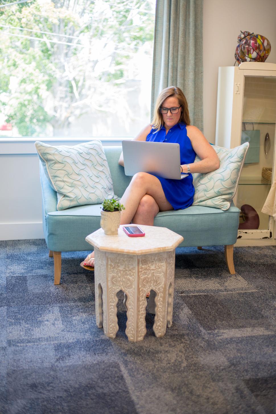 Free Image of Professional woman working on a laptop seated on a sofa 
