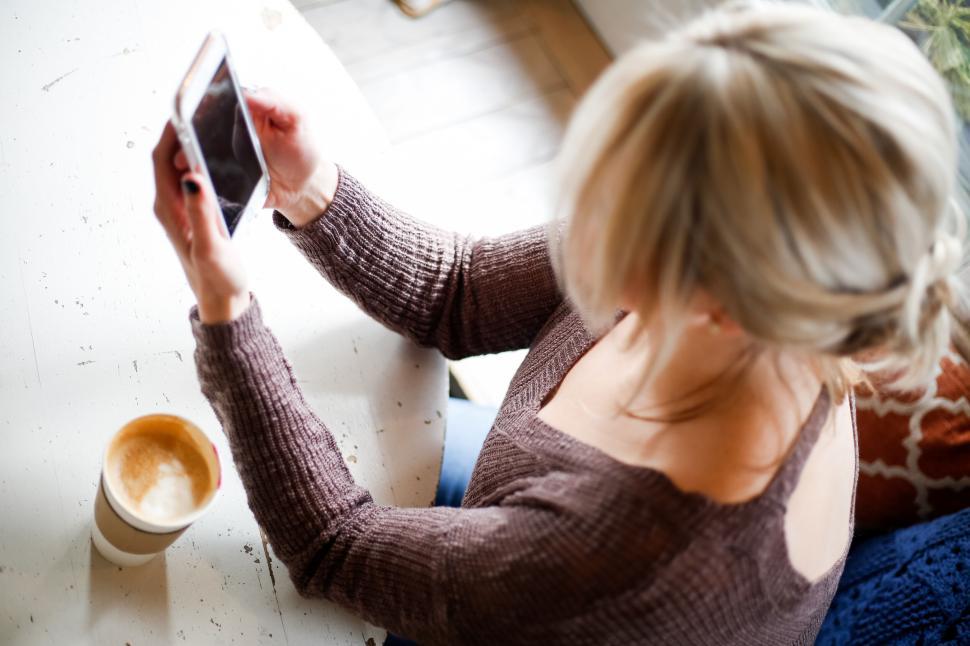 Free Image of Woman with blond hair using smartphone and drinking cappuccino 