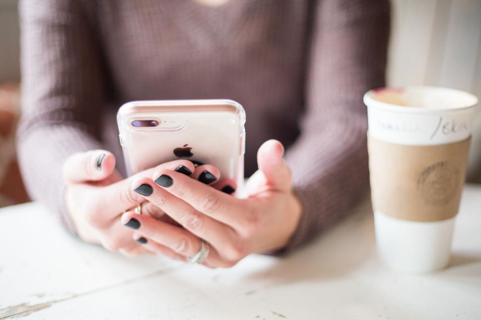 Free Image of Woman using smartphone with coffee on white tabletop 