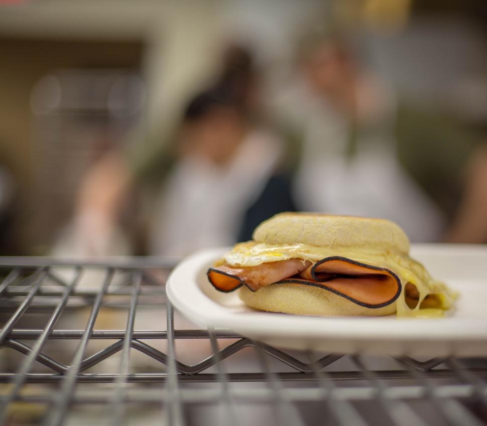 Free Image of Ham and cheese sandwich on a white plate with blurred background. 