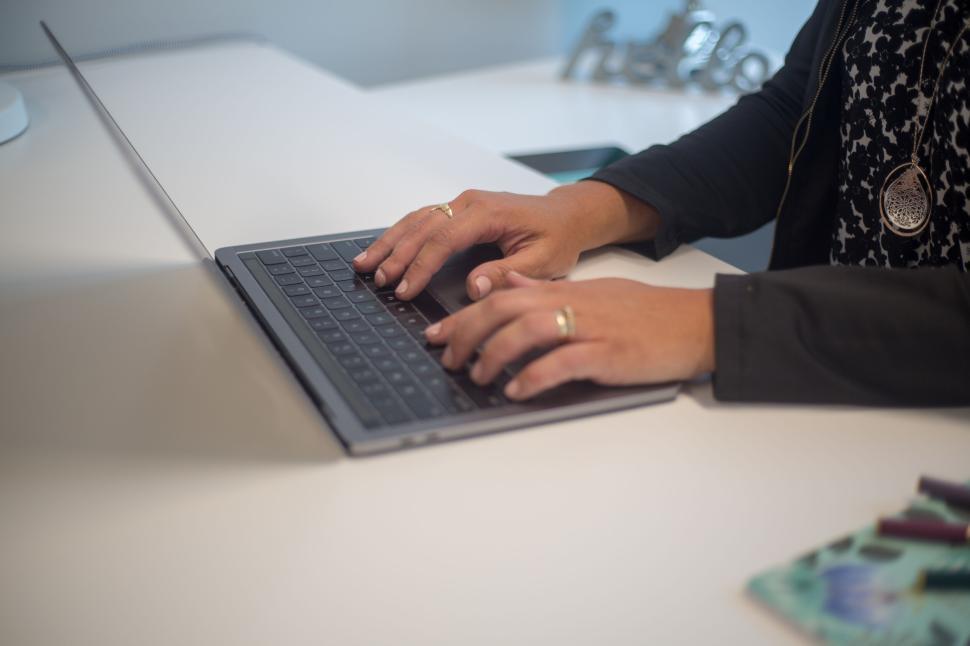 Free Image of Person typing on a laptop keyboard at a modern office desk 