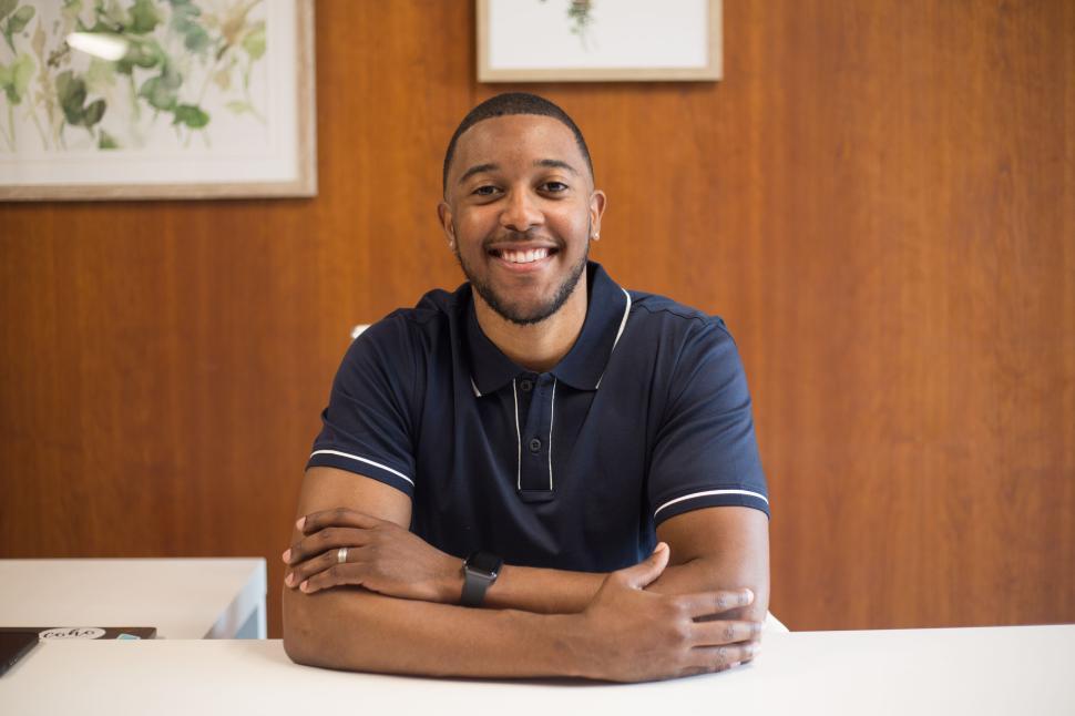smiling-man-in-navy-polo-shirt-seated-wi