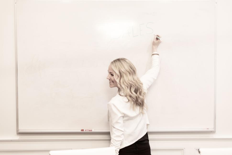 Free Image of Female teacher writing on a whiteboard in a classroom environment 