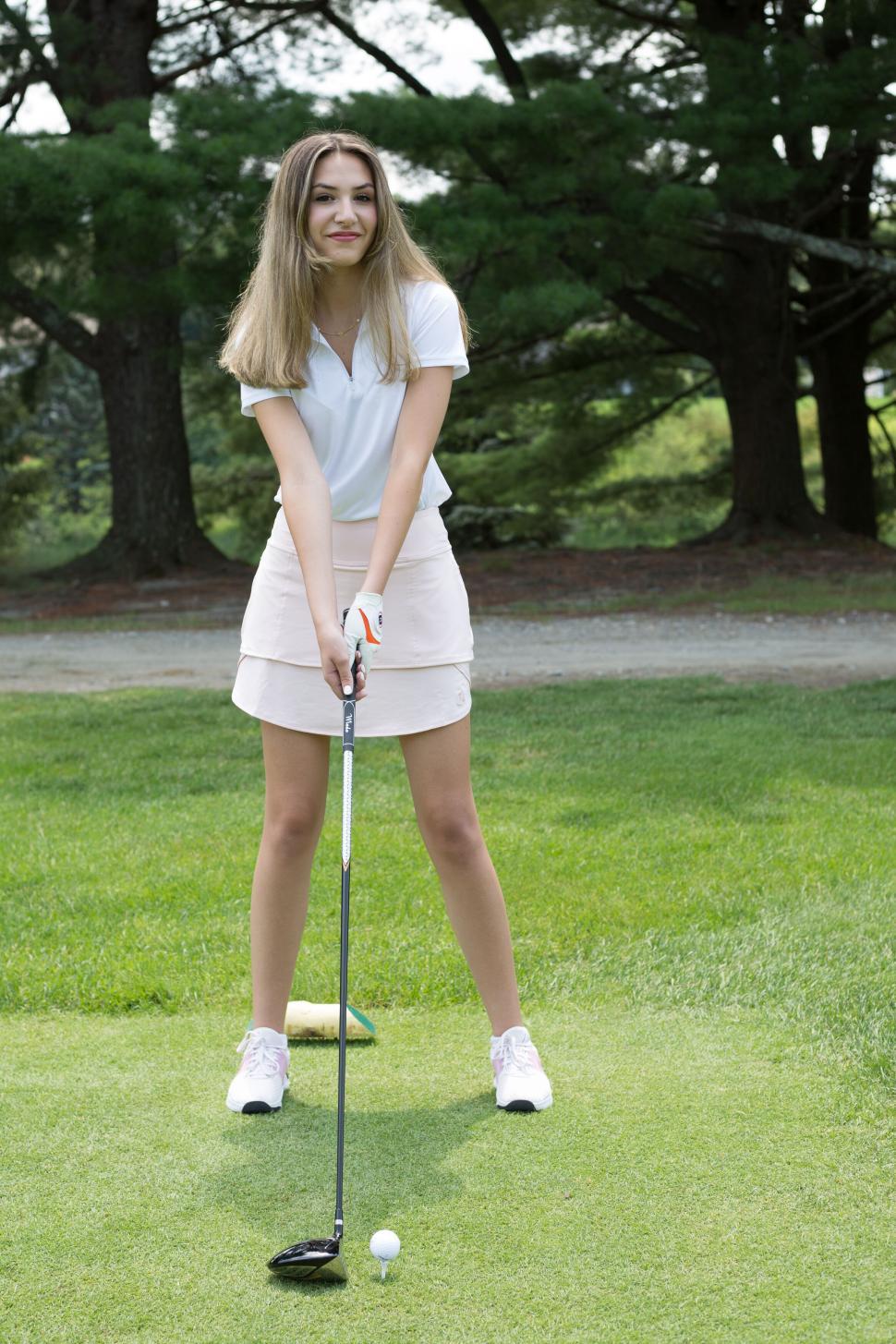 Free Image of Young woman preparing to swing golf club on green outdoors. 