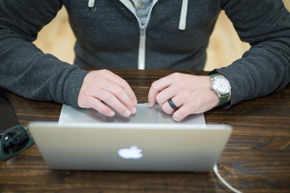 Free Image of Man working on a laptop with a gray hoodie in an office setting 