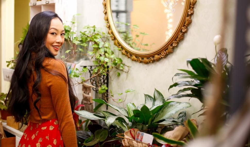 Free Image of Woman standing amidst green plants and smiling warmly. 