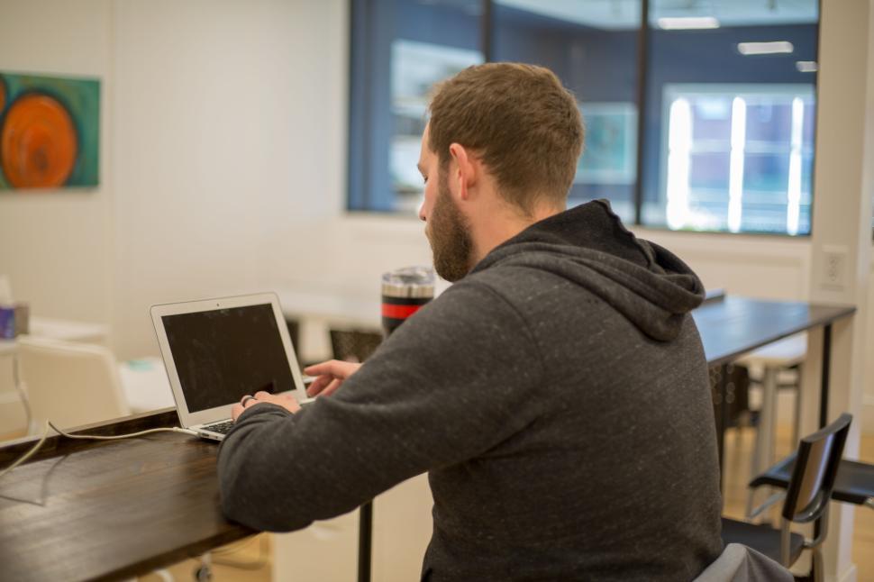 Free Image of Person working on a laptop in a modern open office setting. 