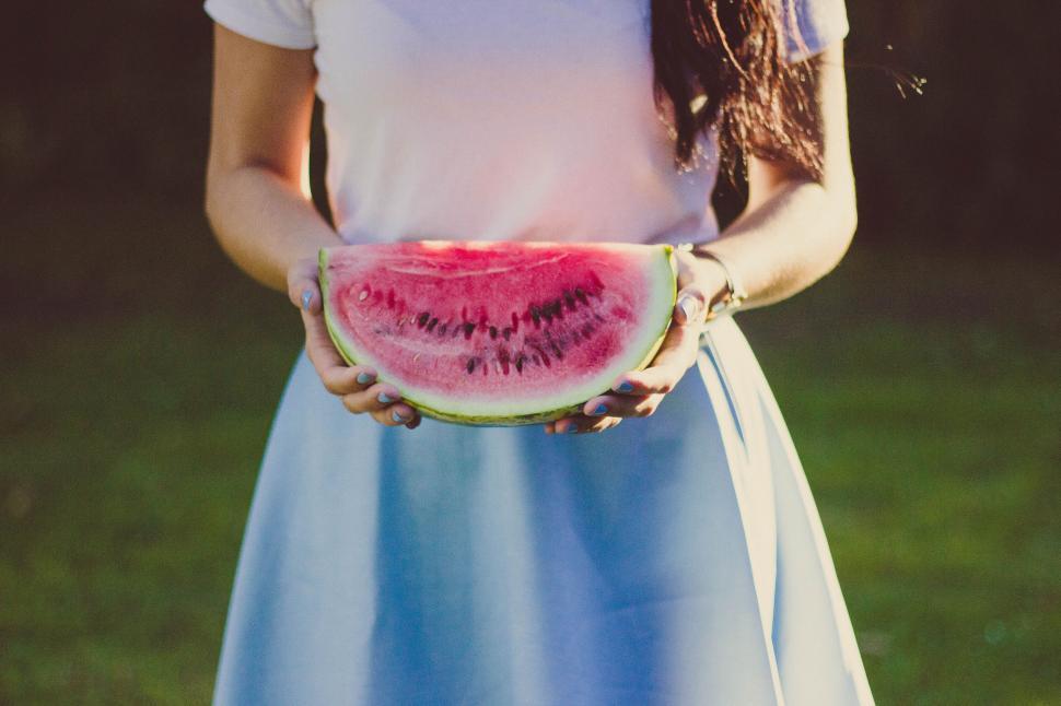 Free Image of Person holding a slice of watermelon in a blue and white outfit 